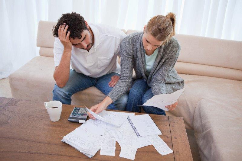 Depressed couple doing their accounting in their living room.